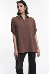 Camisa marrón de manga corta con cuello clásico y cierre frontal con botones.
