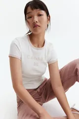 Remera blanca entallada corta en punto acanalado de algodón con estampado frontal "Cannes South of France" en color rosa.