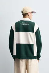 Polo relaxed fit verde oscuro con detalles en blanco, cuello solapa con cierre frontal de botonadura y manga corta. Bordado frontal con la inscripción "Los Angeles California".