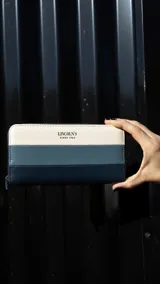 Billetera larga de símil cuero con diseño a rayas horizontales en blanco, azul y azul marino. Cierre perimetral, compartimento interior con tarjeteros y cierre interior. Marca Lincoln's Since 1964.