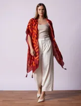 Kimono tejido con estampado geométrico en tonos naranja y borgoña, con terminación de ruedo con borlas.