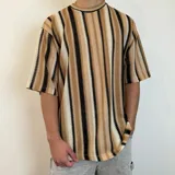 Remera tejida de punto con rayas verticales en tonos beige, marrón y negro, de corte oversize y mangas cortas.