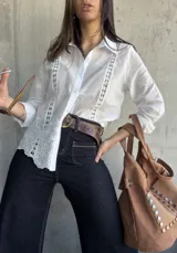 Camisa blanca de manga larga con bordado inglés y cierre frontal con botones.