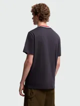 Camiseta de manga corta color blanco hueso con cuello redondo de punto acanalado a rayas en tonos rojo, azul marino y blanco. Presenta un pequeño logo bordado en azul marino en el pecho.