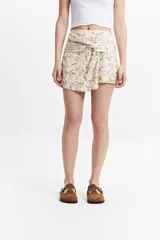 Minifalda pareo estampada en tonos beige y marrón, con diseño anudado frontal que genera un efecto envolvente. Confeccionada en algodón y lino.