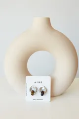 Aros de acero quirúrgico hipoalergénico con forma de argolla plateada y dije circular colgante de piedra natural color azul.