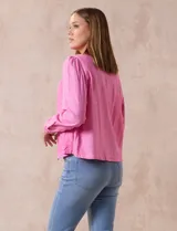 Chaqueta color beige de lino y rayón, con cuello mao, cierre frontal con botones y bolsillos delanteros.