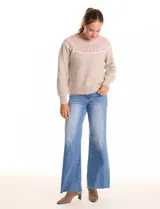 Buzo de punto color beige, con cuello a la base y silueta clásica de hombros relajados. Presenta una guarda tejida con motivos geométricos en tonos rosados, blancos y grises en el canesú. Puños y ruedo con acabado acanalado.