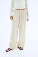 Pantalón de lino color crema, de corte holgado, con cintura elastizada y cordón de ajuste.
