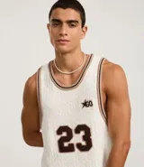 Musculosa de punto color crema con cuello redondo y bies contrastante en marrón. Presenta el número 23 estampado en el frente y un pequeño logo con una estrella.