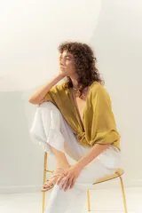 Blusa color mostaza de lino, con escote en V y mangas cortas abullonadas. Se ata en la parte delantera con dos cordones.