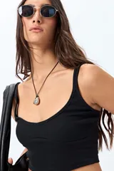 Top corto negro de punto canalé con breteles finos y escote redondeado.