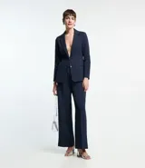 Blazer femenino de corte alargado, color gris oscuro, con cuello solapa, cierre frontal de dos botones y bolsillos incorporados.