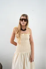 Vestido largo color crema con rayas verticales finas, fruncido en el busto y falda globo. Tiene detalles tejidos de crochet en breteles y escote.
