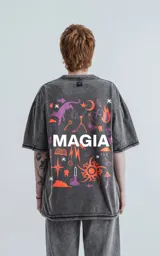 Remera manga corta gris con efecto nevado, cuello redondo y calce oversize. Estampa frontal con la palabra 'MAGIA' en color gris claro.