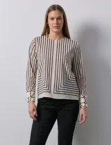Blusa de gasa estampada con líneas verticales negras sobre fondo beige, marca Sioni. Espalda con abertura y botón. Manga larga con puño y botón.