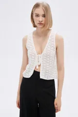 Top sin mangas de algodón color blanco, tejido al crochet, con escote en V profundo y lazo de ajuste en el frente.