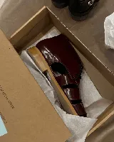 Zapato acordonado de cuero vacuno color marrón con aberturas laterales y cordones negros.