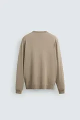 Jersey de hombre color beige claro, tejido en lana, de corte recto, cuello redondo y mangas largas con terminaciones en rib.