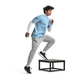Pantalón de jogging gris de corte ajustado, con cintura elástica ajustable con cordón, bolsillos laterales con cierre y logo de Nike bordado en negro en la pierna izquierda.