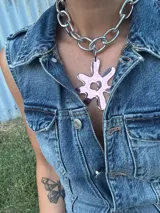 Collar con cadena gruesa plateada y dije abstracto desmontable en acrílico y resina color rosa. El dije puede quitarse para usar la cadena sola.