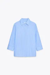 Camisa celeste a rayas verticales blancas, de cuello solapa y manga tres cuartos. Tiene aberturas laterales en el ruedo y cierre frontal con botones ocultos.
