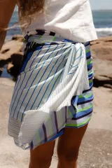 Pareo rectangular de viscosa con estampado de flores rojas sobre fondo borgoña y borde inferior con rayas verticales rojas, amarillas y blancas.