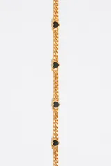 Collar dorado con cadena de eslabones y pequeños dijes de corazones negros.
