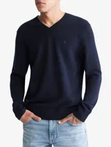 Sweater liso de lana merino azul con escote en V, puños y dobladillo en punto canalé, y monograma de Calvin Klein bordado.