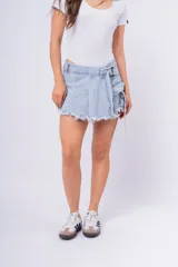 Short pollera de jean celeste con cintura alta, corte evasé, detalle de cinturón con hebilla metálica y terminación desflecada.