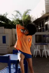 Buzo naranja de algodón con cuello en V y bordado en el frente. Tiene mangas largas con puños y ruedo acanalados.