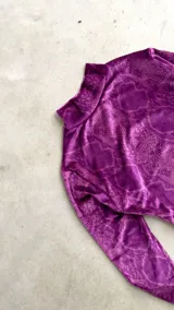 Body de terciopelo marrón con estampado de piel de serpiente, cuello alto, mangas largas con orificio para el pulgar y espalda descubierta.