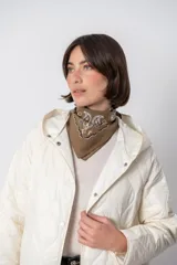Campera color crema con diseño acolchado en forma de rombos, capucha y cierre con botones a presión.