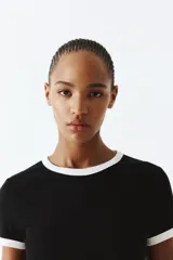 Remera negra entallada de punto suave con cuello y mangas con ribete blanco.