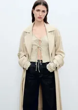 Abrigo largo color beige con cuello de solapa, trabillas en los hombros y cinturón tipo batín.