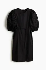 Vestido a la rodilla negro en tejido liviano de algodón con cuello redondo, botones ocultos adelante y cinturón para atar fino extraíble. Mangas al codo abullonadas en broderie con puños elásticos.