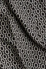 Pantalón de tiro alto con elástico en la parte posterior de la cintura y cierre oculto lateral. Presenta bolsillos discretos en las costuras laterales y piernas anchas con pliegues adelante y atrás. Diseño estampado con motivos geométricos en blanco y negro.