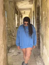 Buzo deportivo de color azul claro, estilo oversize, con cuello redondo y puños y ruedo con elástico. Presenta un pequeño logo bordado en el pecho.