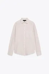 Camisa color crudo de corte recto, con cuello clásico, manga larga con puños abotonados, cierre frontal con botones y bolsillo de parche en el pecho.