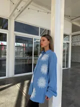 Camisa celeste con estampado de flores blancas, de corte holgado y manga larga.