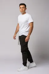 Pantalón cargo color beige de gabardina, con corte ajustado, bolsillos laterales con fuelle y puños elásticos en los tobillos.