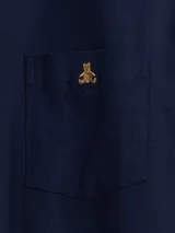 Camisa de manga larga color beige, de corte clásico, con cuello abotonado, bolsillo en el pecho y logo de oso bordado.