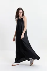 Vestido largo negro con estampado abstracto, de silueta amplia, con breteles finos y escote redondeado. Tiene un frunce sutil en el escote delantero y trasero que genera una caída fluida y relajada.