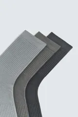 Pack de tres pares de calcetines de caña media, tejidos en punto acanalado en tonos de gris.