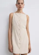 Vestido corto color crema, de corte recto, con tirantes finos, escote cuadrado y cierre frontal con botones.