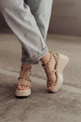 Sandalias negras de plataforma con tiras de gamuza y esferas doradas decorativas.