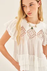 Camisa azul de algodón liviano con cuello redondo y gota en la espalda. Presenta detalle de bordado calado, terminación de volado en mangas y ruedo.