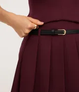 Short pollera de sastre color bordó, con cintura con trabillas y textura plisada. Incluye un cinturón fino de material sintético negro.