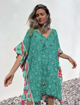 Túnica corta verde con estampado de flores rojas y detalles bordados. Mangas anchas con terminación en volados con estampado floral en tonos rosa y celeste.