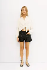 Short cargo negro de cuero vacuno, con múltiples bolsillos frontales con cierres y solapas. Corte por encima de la rodilla.